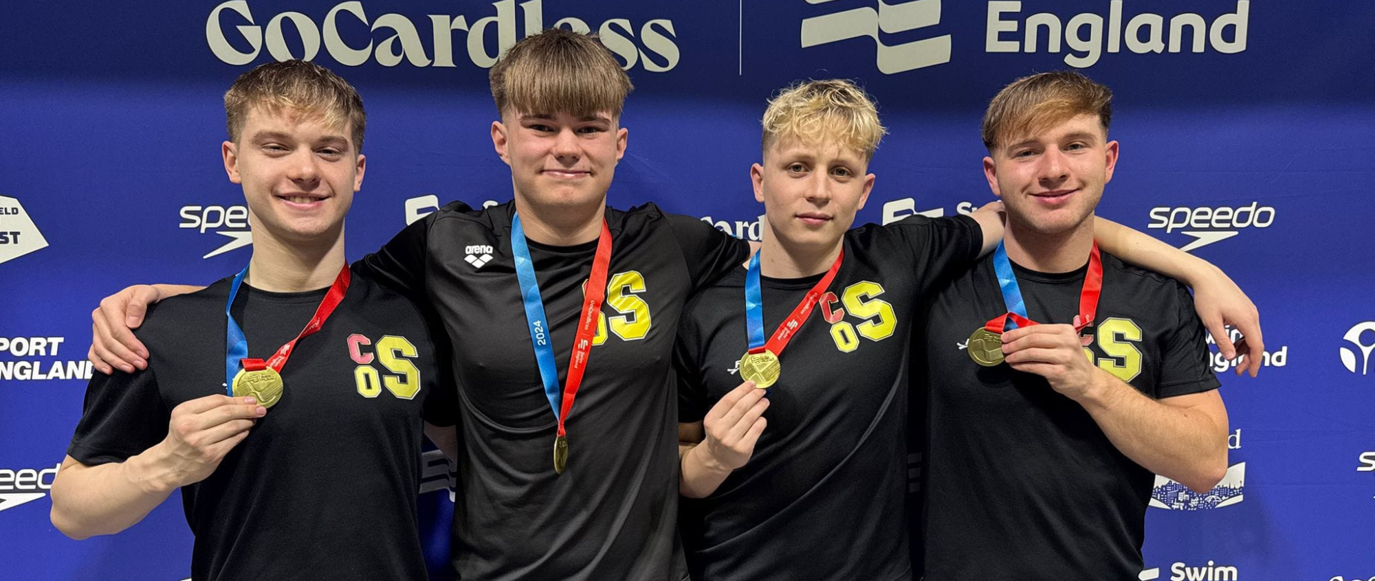 Five boys standing with various medals