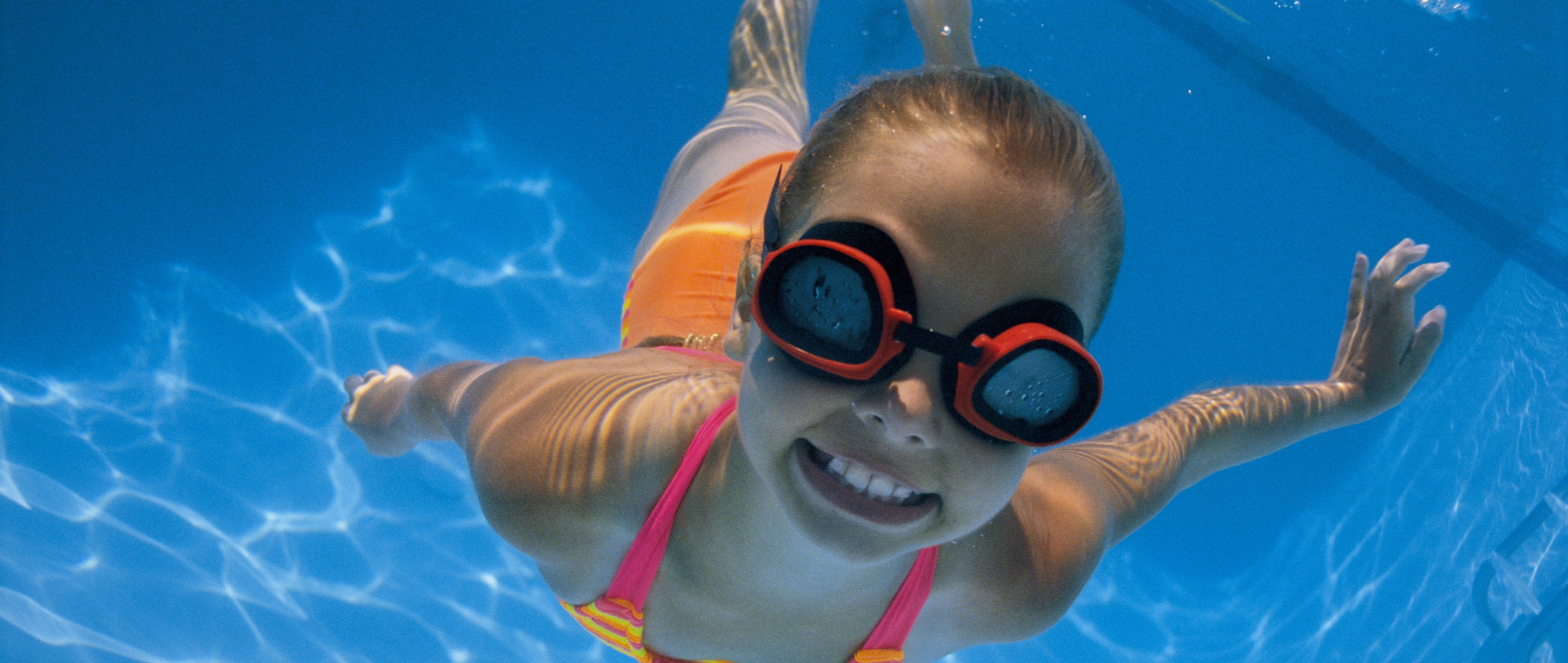 Young girl swimming in pool with goggles