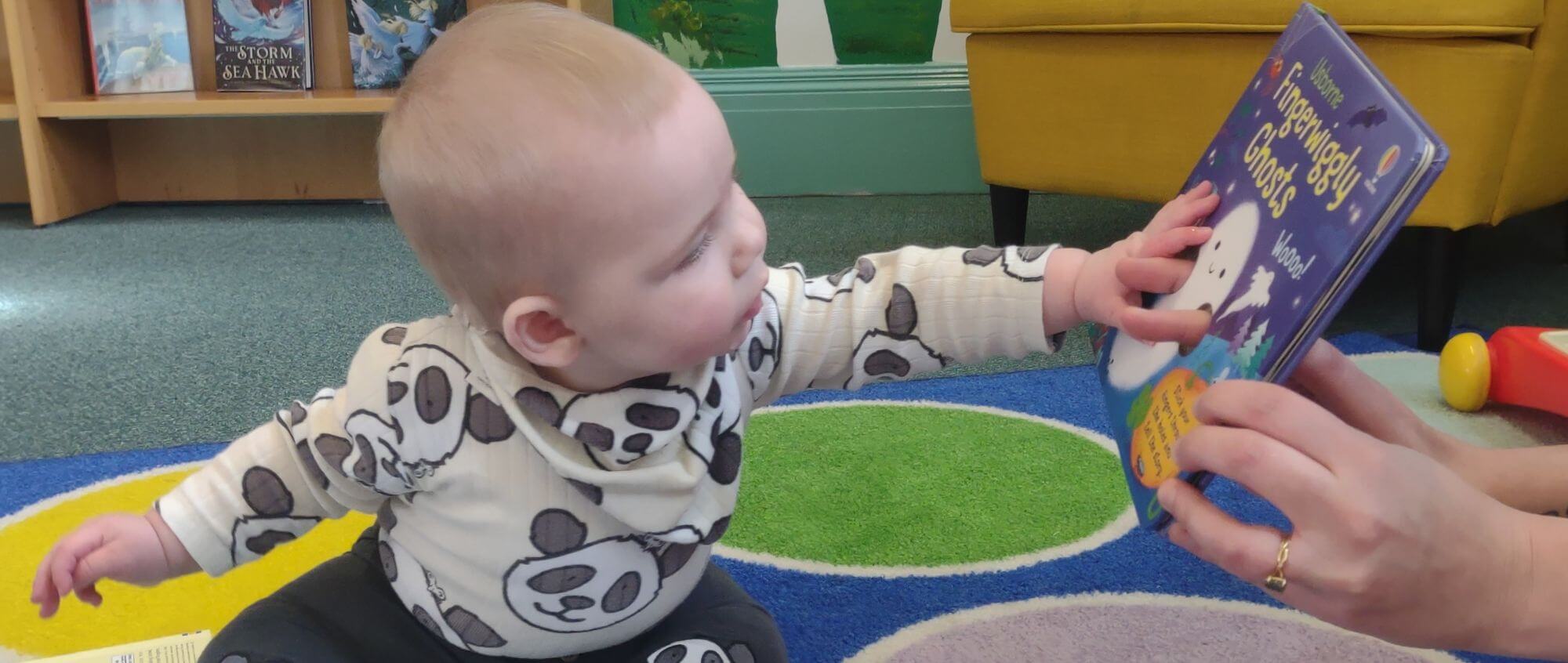 A baby interacts with a book in a library