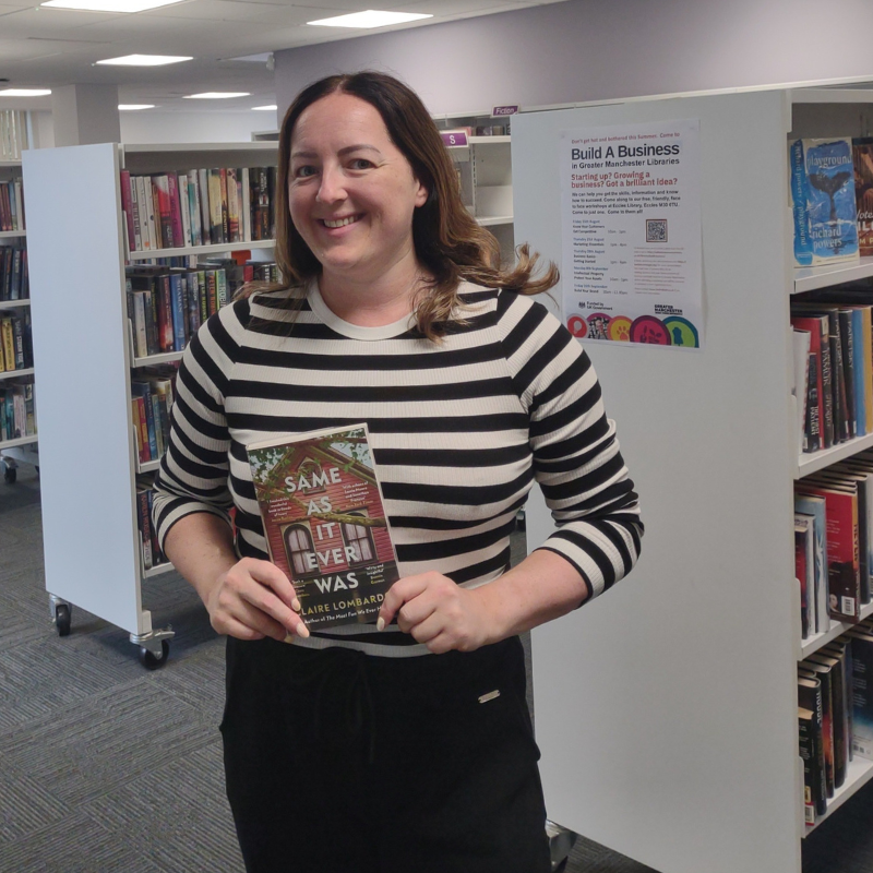 Beth stands in Swinton Library holding a book