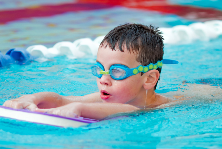 Young boy swimming on a float in pool