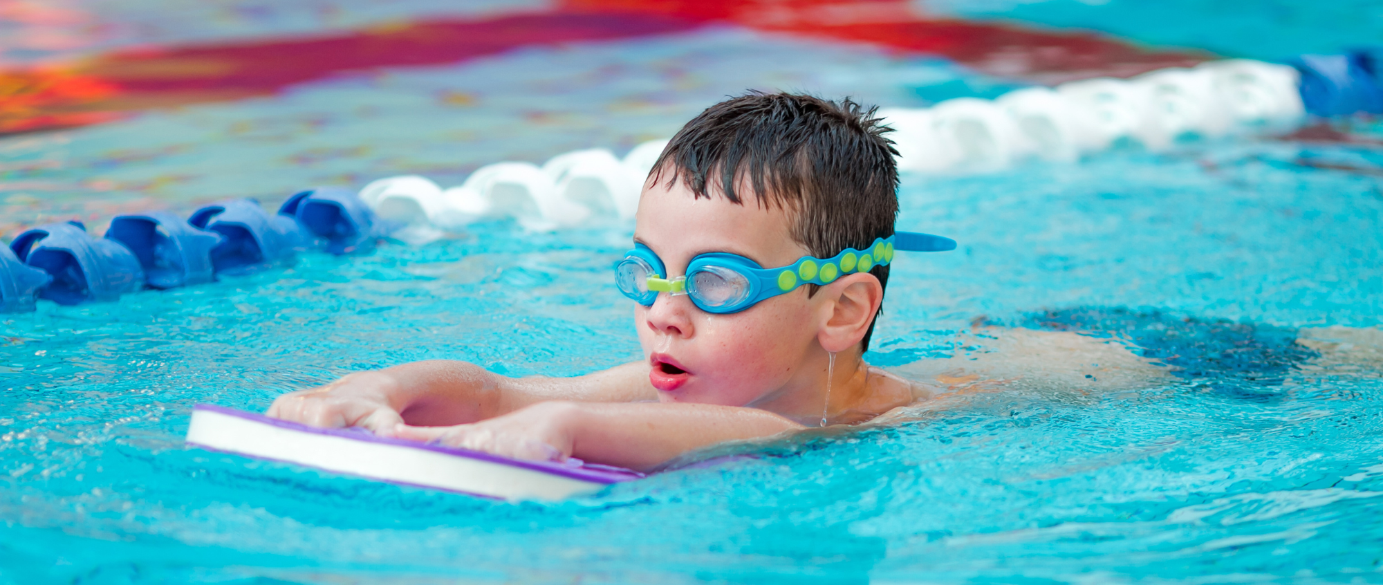 Young boy swimming on a float in pool