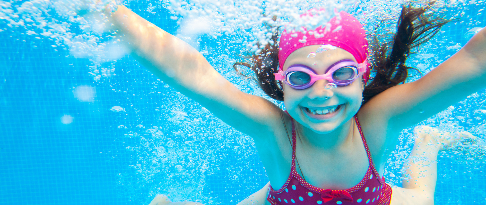 Girl swimming underwater with goggles and swimming hat