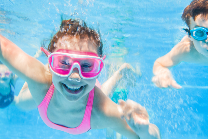 Girl and boy swimming underwater with goggles