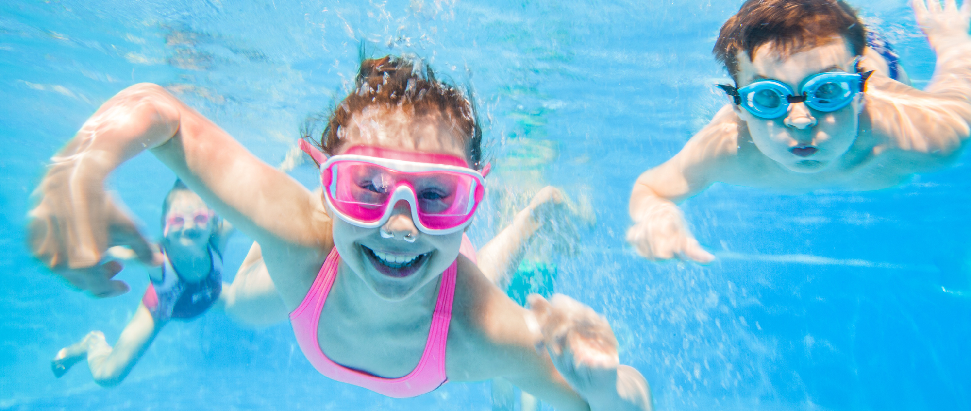 Girl and boy swimming underwater with goggles