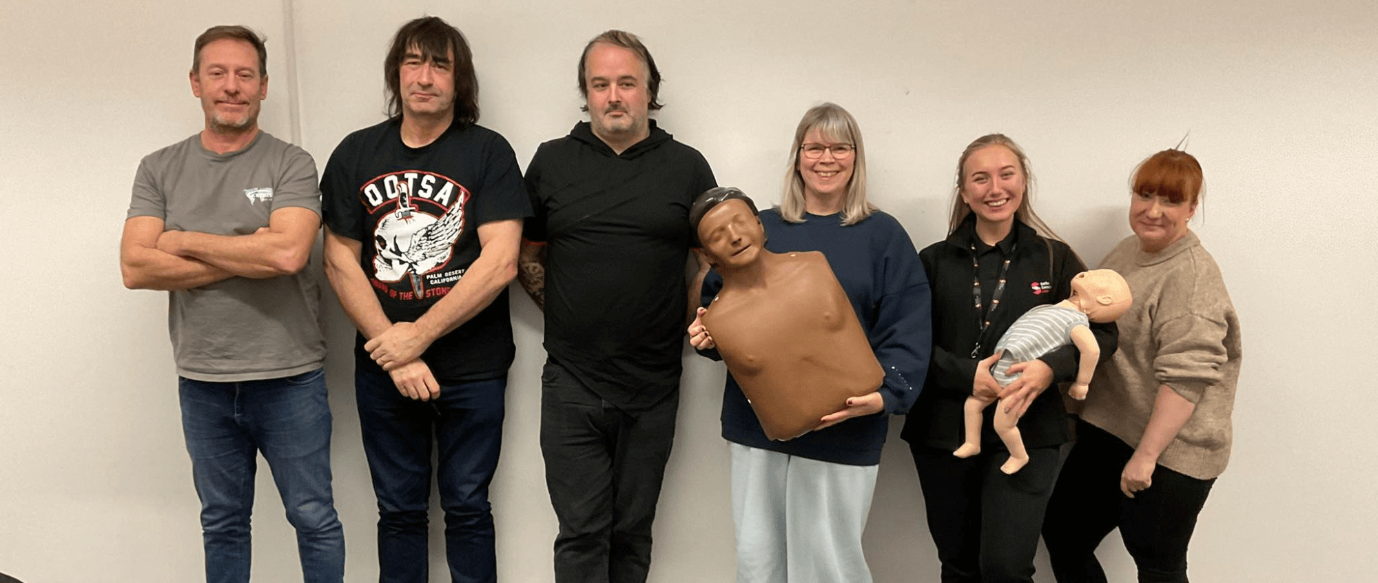 Group of people holding a dummy following completed training
