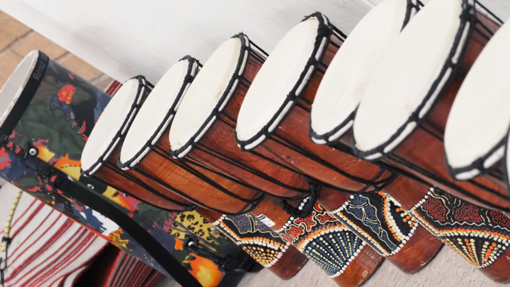 Djembe drums in a line against a wall