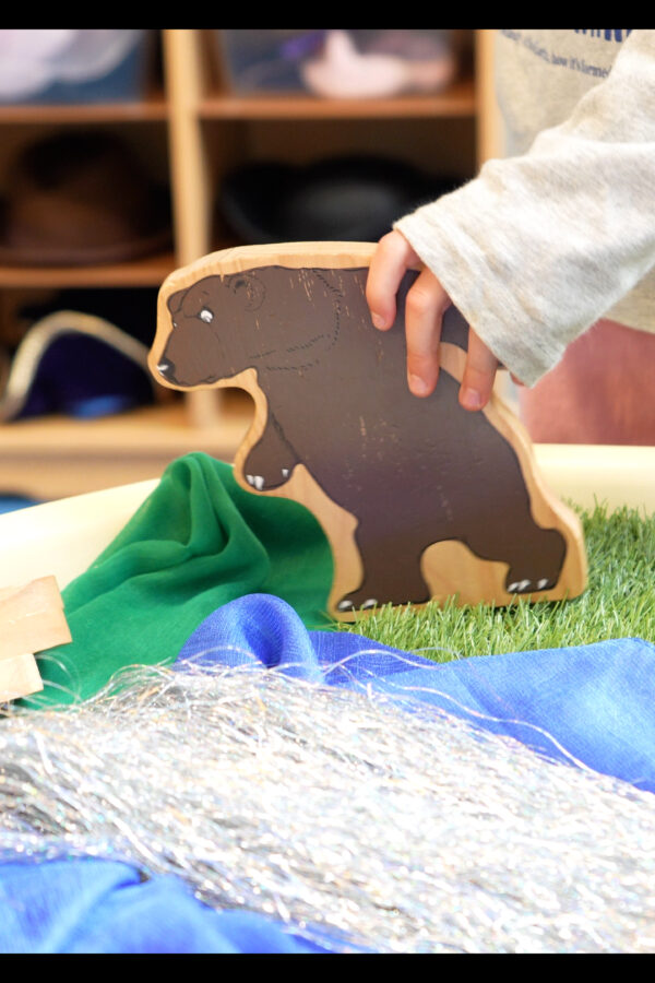 Child's hand playing with a bear toy at Salford Library Storynook