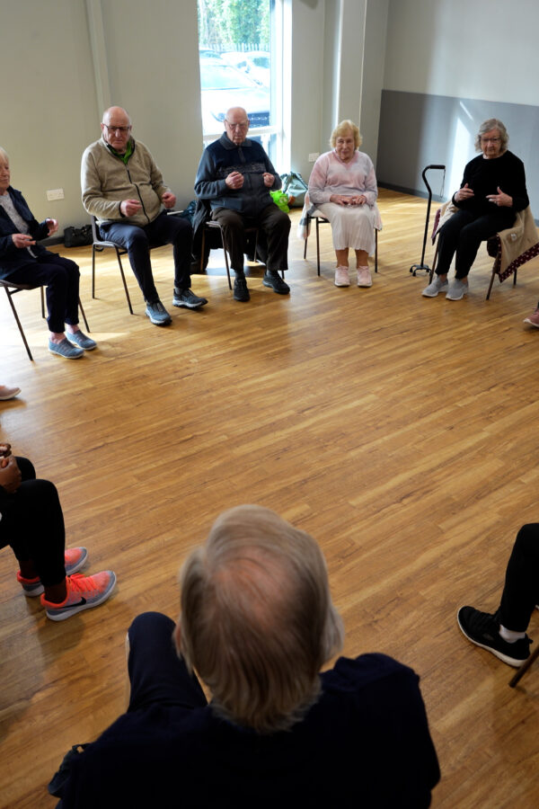 People sitting on chairs in a circle in a can move class