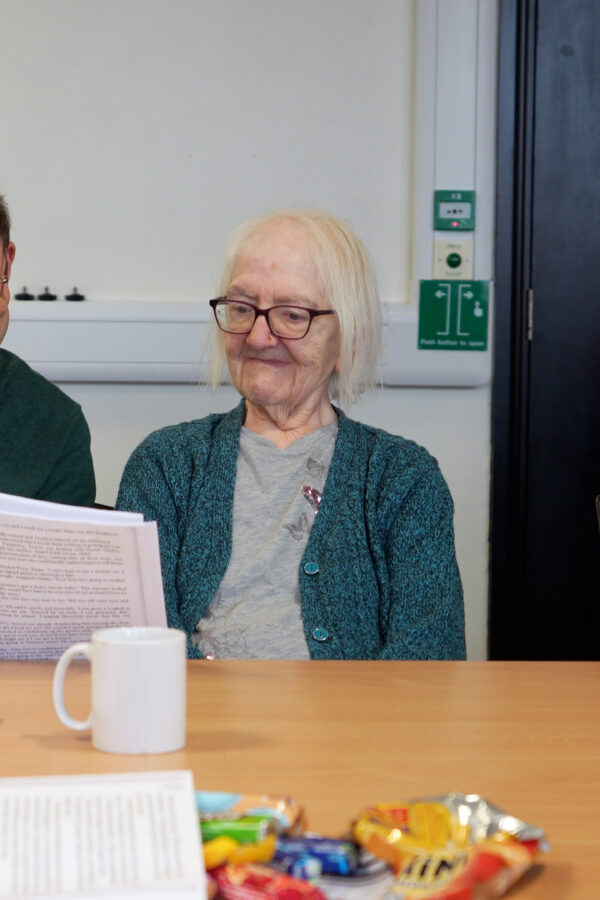 A man and older lady reading from a paper together in a Salford Library group
