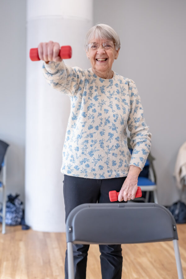 Smiling Lady taking part in exercise on referral with a small hand weight