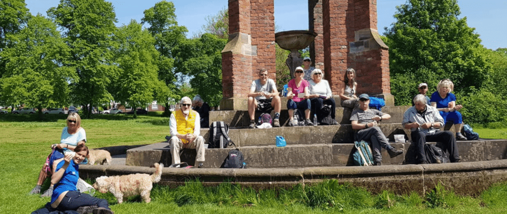 A group of volunteers sitting on a park bandstand