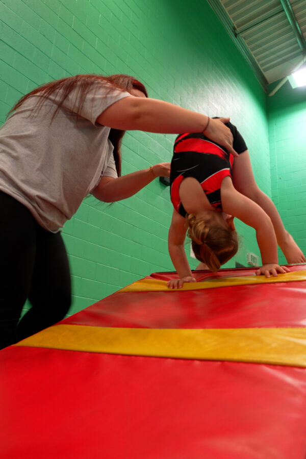 young girl being helped to do a forward roll