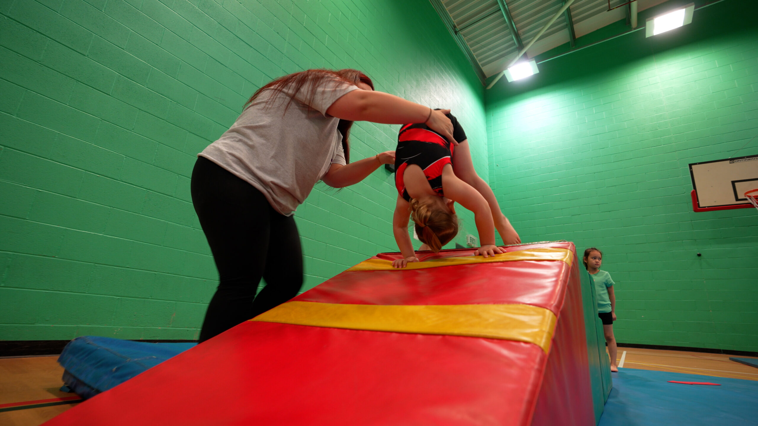 young girl being helped to do a forward roll